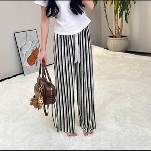 Detail of high-waisted black and white striped wide-leg trousers with white drawstring