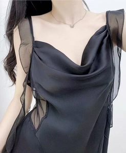 Detail of black satin slip dress with cowl neck and sheer mesh ruffles on shoulders