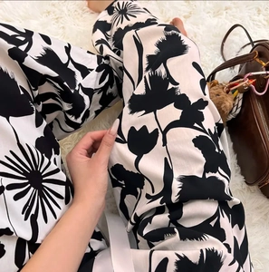 Macro detail of breathable black floral print wide-leg pajama pants on white rug