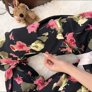 Detailed view of floral pattern wide-leg pajama pants on soft white carpet background