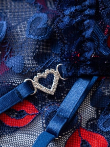 Detailed macro view of dark blue lace with red lips and a sparkling heart rhinestone buckle