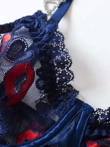 Close-up of blue lace lingerie with red lip prints and a silver heart rhinestone buckle