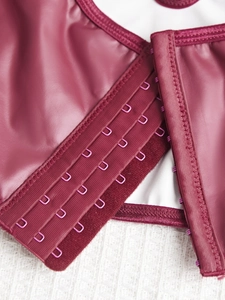 Detailed close-up of multi-row metal hook-and-eye closures on burgundy faux leather corset
