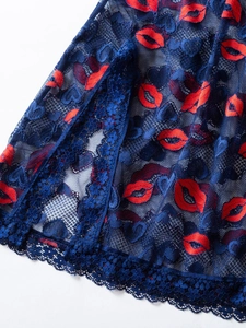 Detailed close-up of dark blue lace fabric featuring red lip prints and scalloped edges