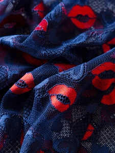 Close-up of dark blue lace fabric featuring red lip prints and intricate mesh texture