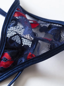 Detailed macro view of dark blue lace fabric with red lip patterns and satin piping detail