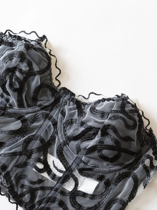 Detailed view of the black floral embroidery and delicate mesh texture on a strapless corset