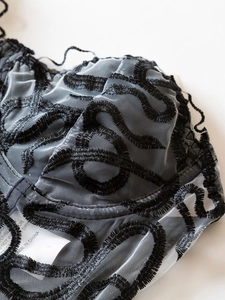 Close-up of intricate black embroidery on a semi-transparent mesh lace bustier top