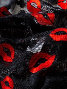 Close-up of black lace fabric featuring vibrant red lip patterns and fine mesh texture