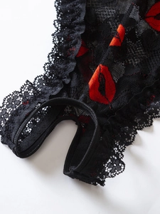 Detail of black floral lace lingerie with red lip prints and open crotch design