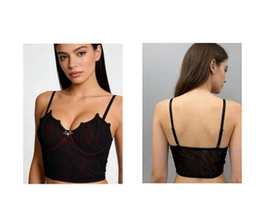 Detail view of Gothic bat-wing corset top with metal pendant and red textured fabric