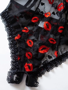Close-up of black lace lingerie with red lip prints and elegant scalloped lace edges