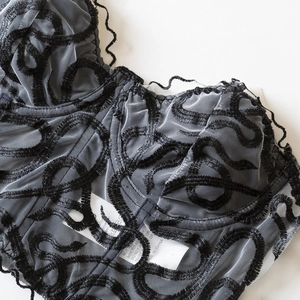 Front view of black strapless lace corset top with floral embroidery and mesh detail