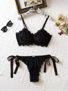 Détail d'un ensemble de lingerie en dentelle noire avec soutien-gorge push-up et culotte à nœuds