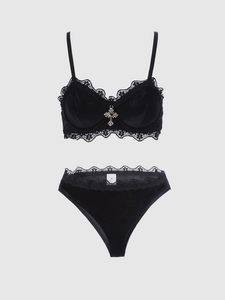 Dettaglio di lingerie in velluto nero con pizzo e ciondolo a croce in argento