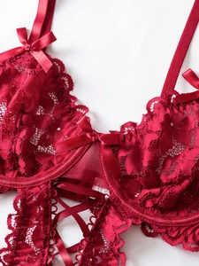 Detailed view of red floral lace bodysuit with satin bows and cross-tie ribbons