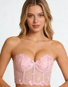 Detail of pink floral lace corset featuring mesh texture and a sweet ribbon bow