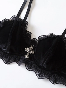 Dettaglio del reggiseno in velluto nero gotico con pizzo e ciondolo a croce argento