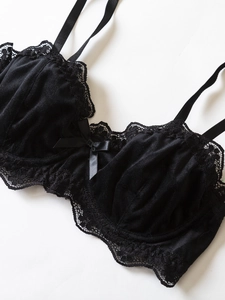 Detail of black velvet bra with delicate floral lace trim and satin bow decoration