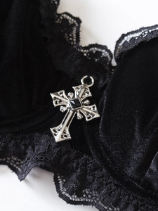Dettaglio macro di lingerie gotica in velluto con pizzo e ciondolo a croce d'argento
