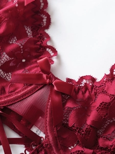 Close-up of red floral lace detail with satin bow and breathable mesh fabric