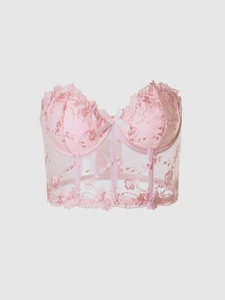 Detail of pink mesh corset top with floral lace embroidery and a small ribbon bow