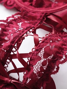 Detail of dark red floral lace with satin ribbon ties and scalloped edges on lingerie