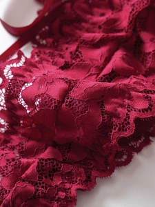 Macro shot of dark red floral lace texture and silk ribbon on sexy lingerie bodysuit