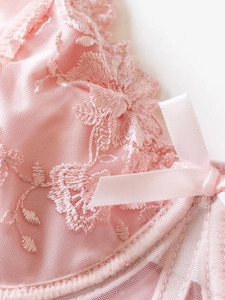 Detail of pink floral lace embroidery and sheer mesh with a delicate satin bow