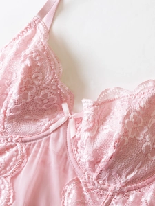 Close-up of pink floral lace corset with delicate mesh texture and bow detail
