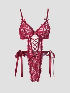 Macro shot of dark red floral lace texture and decorative ribbon bow on seductive bodysuit