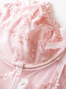 Close-up of pink mesh corset with floral embroidery and delicate satin bow detail