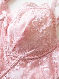 Close-up of pink floral lace cup with satin bow detail and scalloped edges on corset