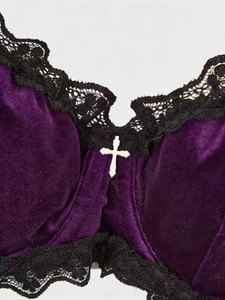 Detail of dark purple velvet bra featuring delicate black lace and a silver cross pendant