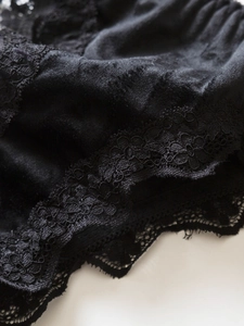 Detail of black satin lingerie featuring delicate floral lace trim and smooth fabric