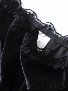Dettaglio di velluto nero con pizzo floreale ed etichetta taglia S sul retro del collo