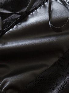 Detail of black PU leather corset showing litchi texture with delicate lace trim