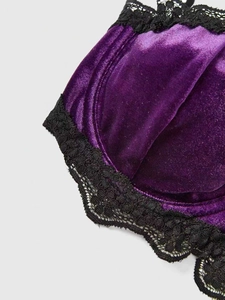 Detail of purple velvet bra cup featuring intricate black lace trim and stitching