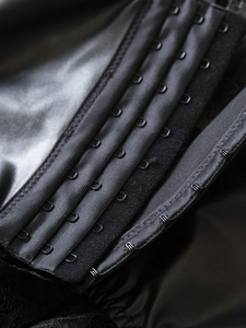 Macro detail of black PU corset featuring four-row hook-and-eye closure and lace trim