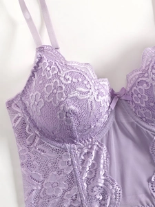 Detail view of lavender lace corset with floral patterns and delicate ribbon bow detail