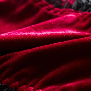 Detailed close-up of dark red velvet fabric with elegant black lace trim accents