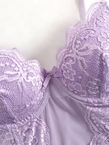 Close-up of lavender floral lace with mesh stitching and a small ribbon bow detail