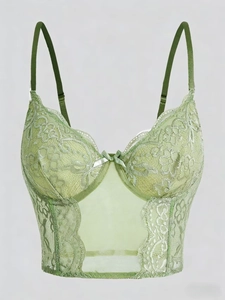 Detailed close-up of light green floral lace bustier featuring a delicate satin bow accent