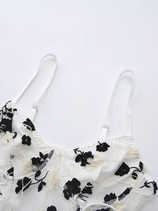 Detail of white mesh camisole featuring intricate floral embroidery and adjustable straps