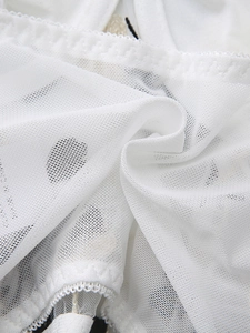 Detailed macro view of white breathable mesh fabric with black polka dots and lace trim