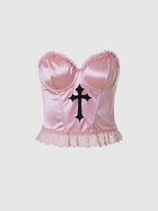 Detail of pink satin corset top with black cross applique and delicate lace trim edge