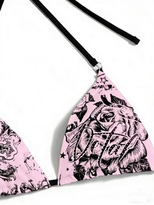 Detail of pink bikini top with rose and star prints, featuring black straps and metal rings