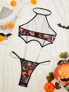 Detail von sexy orangefarbenem Halloween-Dessous mit Totenkopfprint und Metallketten