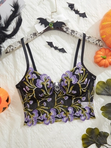 Detail of floral embroidery on black mesh bustier with heart charm and pumpkin decorations