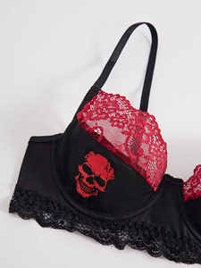 Detail of red floral lace trim and gothic skull print on black underwire bra cup